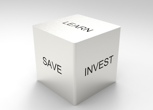 A three-dimensional cube with words on its visible sides, featuring 'LEARN' on the top, 'SAVE' on the left face, and 'INVEST' on the right face. The cube is rendered in a minimalist white and gray color palette, creating a clean and professional look.