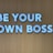 Large white letters spelling 'BE YOUR OWN BOSS' are mounted on a wooden wall, conveying empowerment and independence.